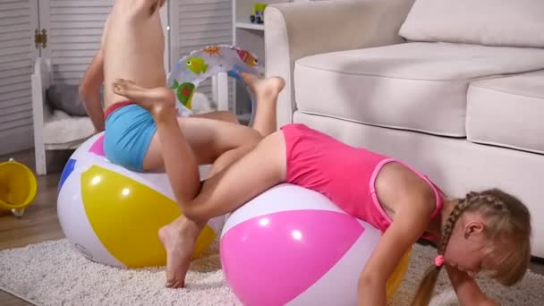 As crianças têm o divertimento sentam-se e saltam em bolas infláveis de borracha grandes na sala de jogos — Vídeo de Stock