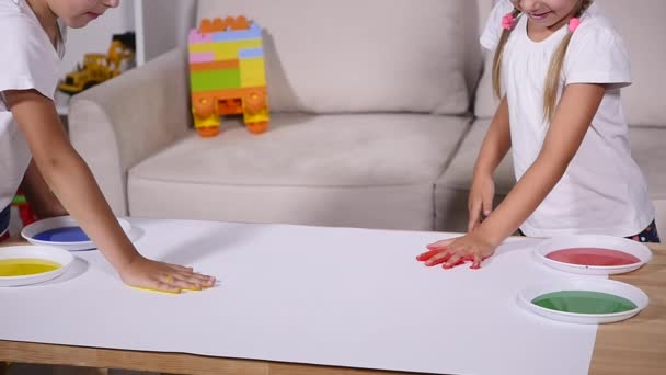 A little cute happy funny child painting color handprints on the white sheet of paper — Stock Video