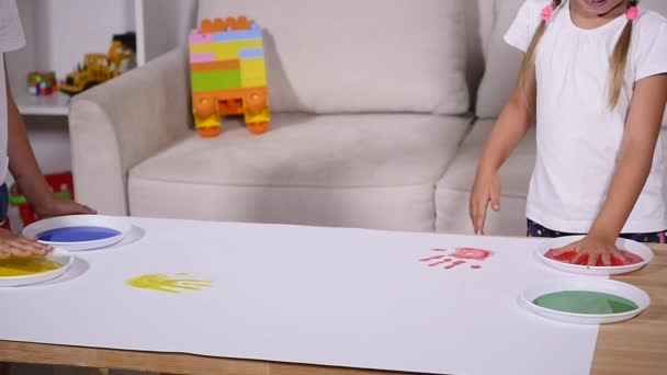 A little cute happy funny child painting color handprints on the white sheet of paper — Stock Video