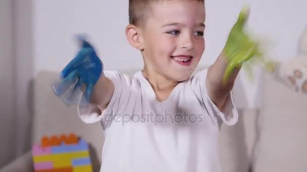 Hermoso niño con las manos en la pintura. Retrato del niño risueño y juguetón. Primer plano de alegre chico divertido aislado sobre fondo blanco — Vídeos de Stock