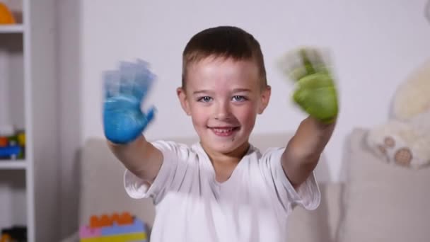 Hermoso niño con las manos en la pintura. Retrato del niño risueño y juguetón. Primer plano de alegre chico divertido aislado sobre fondo blanco — Vídeos de Stock