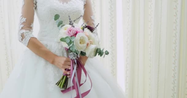 Beau bouquet de mariée entre les mains d'une jeune mariée vêtue d'une robe de mariée blanche. Gros plan de gros bouquet de roses blanches fraîches dans les mains des femmes. Mariée anonyme tenant des fleurs — Video