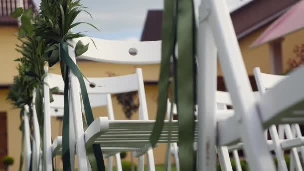 Hochzeit im Garten, Park. außerhalb Hochzeitszeremonie, Feier. Hochzeitsgang Dekor. Reihen weißer Holzstühle auf dem Rasen vor der Trauung — Stockvideo