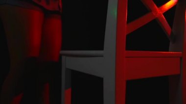 Seksi bir kız bir inç kısa şort ve tişört siyah arka plan üzerine bir sandalyede oturur