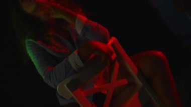 Seksi bir kız bir inç kısa şort ve tişört siyah arka plan üzerine bir sandalyede oturur