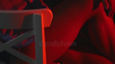 Seksi bir kız bir inç kısa şort ve tişört siyah arka plan üzerine bir sandalyede oturur