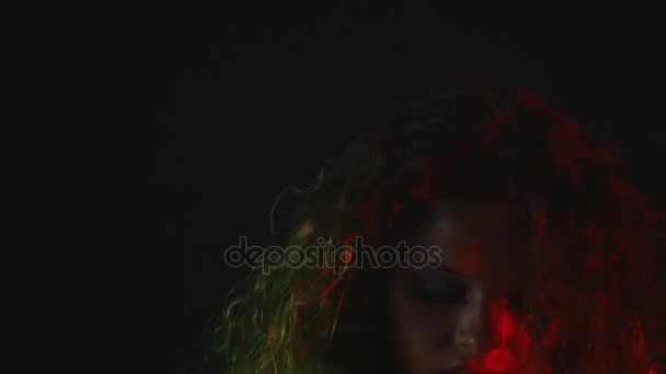 Une fille sexy s'assoit sur une chaise dans un short et une chemise sur fond noir 