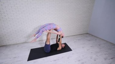 Güzel çift Acro yoga uygulamak. Genç yoga eğitmenleri pratik bir stüdyoda. İki başarılı gençler acro yoga egzersizleri gerçekleştirmek
