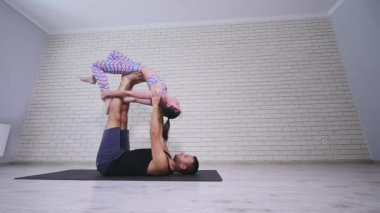 Güzel çift Acro yoga uygulamak. Genç yoga eğitmenleri pratik bir stüdyoda. İki başarılı gençler acro yoga egzersizleri gerçekleştirmek