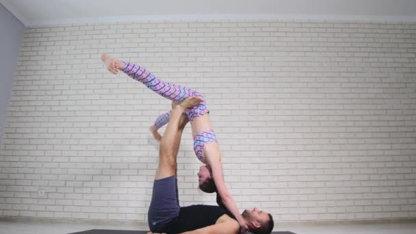 Hermosa pareja haciendo acro yoga en estudio — Vídeos de Stock