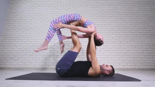 Akrobatisk yoga. Ung kvinna och man utför övningar. Kombinationen av akrobatik och yoga — Stockvideo