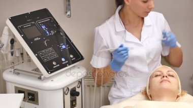 Genç güzel kadın klinik tabloyu, güzellik uzmanı yalan onu yüz elektro-stimülasyon masaj yapar. Kaldırma yordamı, donanım kozmetik. Lüks yaşam tarzı, modeli faaliyetleri