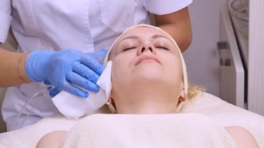 Kadın kozmetik prosedür sırasında kanepede yatıyor. Profesyonel güzellik uzmanı yüz spa salonda masaj yapıyor. Yüz bakımı. Güzellik, sağlıklı ve genç kavramı