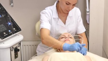 Genç güzel kadın klinik tabloyu, güzellik uzmanı yalan onu yüz elektro-stimülasyon masaj yapar. Kaldırma yordamı, donanım kozmetik. Lüks yaşam tarzı, modeli faaliyetleri