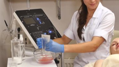 Güzellik uzmanı bir tüp krem bir cam daire sıkar. Medecine eldiven elinde