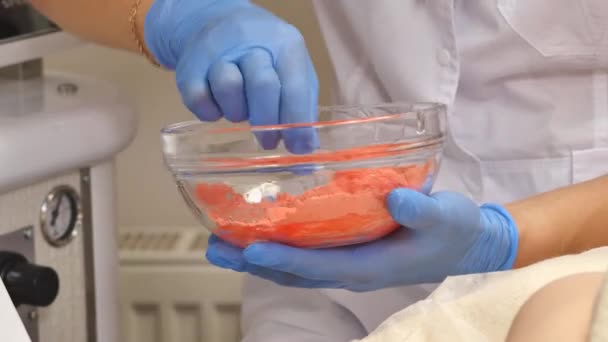 Косметолог стискає крем з трубки на скляній тарілці. Рукавички в медичних рукавичках — стокове відео