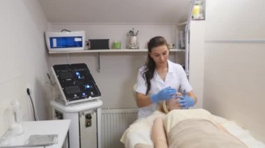 Kadın kozmetik prosedür sırasında kanepede yatıyor. Profesyonel güzellik uzmanı yüz spa salonda masaj yapıyor. Yüz bakımı. Güzellik, sağlıklı ve genç kavramı