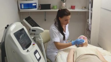 Kozmetik masanın üzerinde yatan kapalı gözler, güzel bir kadınla dermatolog profesyonel hasta yüzü temiz. Yüz bakımı, sağlıklı olmak mutlu olmak,