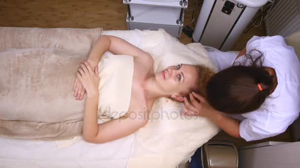 A mulher está deitada no sofá durante o procedimento cosmético. Vista superior — Vídeo de Stock
