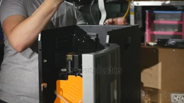 Adam kapağı kahve makinesinde koyar.