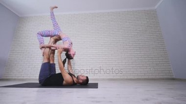 Güzel çift Acro yoga uygulamak. Genç yoga eğitmenleri pratik bir stüdyoda. İki başarılı gençler acro yoga egzersizleri gerçekleştirmek