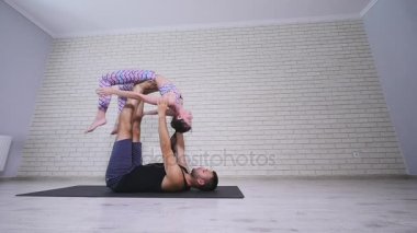 Güzel çift Acro yoga uygulamak. Genç yoga eğitmenleri pratik bir stüdyoda. İki başarılı gençler acro yoga egzersizleri gerçekleştirmek
