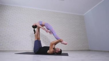 Güzel çift Acro yoga uygulamak. Genç yoga eğitmenleri pratik bir stüdyoda. İki başarılı gençler acro yoga egzersizleri gerçekleştirmek