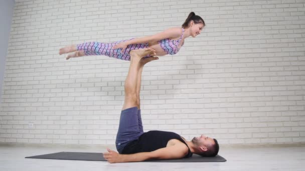 Hermosa pareja haciendo acro yoga en estudio — Vídeos de Stock