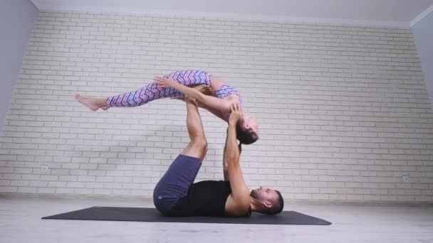 Акробатическая йога. Молодая женщина и мужчина выполняют упражнения. Сочетание акробатики и йоги — стоковое видео