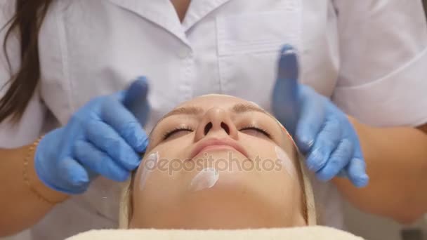 Cosmetólogo aplica crema en la piel del cliente — Vídeos de Stock