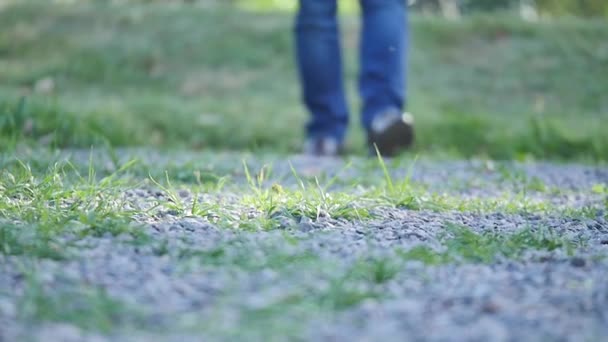 Fiatal férfi sétál az utcán. Közeli kép a lábak, a farmer és a csizma — Stock videók