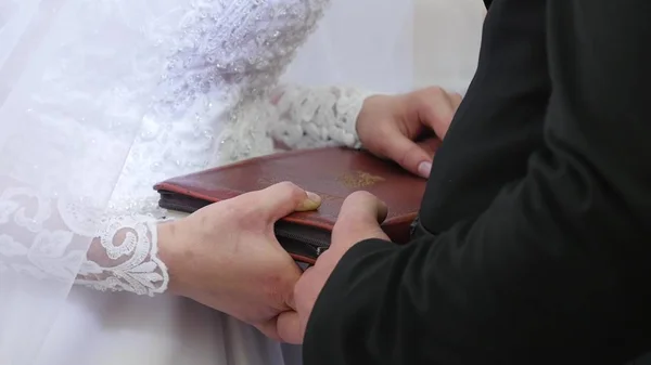 Panna młoda i pan młody ręce na Biblii. Narzeczeni umieścić swoje ręce na Biblii do wymiany śluby. — Zdjęcie stockowe
