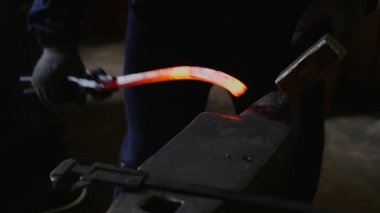 Demirci demir sopa bir çekiç ile eğiliyor.