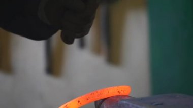 Demirci demir sopa bir çekiç ile eğiliyor.