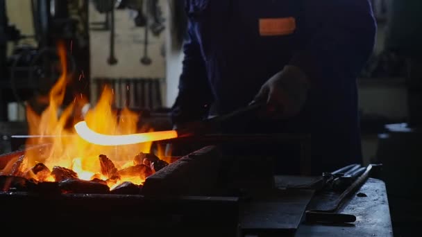 O ferreiro tira o ferro quente do fogo. — Vídeo de Stock