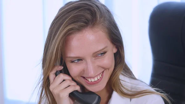 Young attractive businesswoman talking on telephone in the office and smiling. close up — Stock Photo, Image