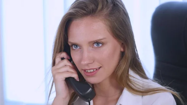 Young attractive businesswoman talking on telephone in the office and smiling. close up — Stock Photo, Image
