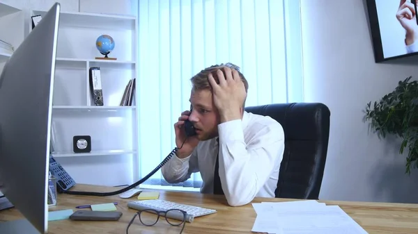Genç iş adamı cep telefonu ve ofis telefon üzerinde konuşmak ve Notlar not defterinde Office masada otururken yapma meşgul — Stok fotoğraf