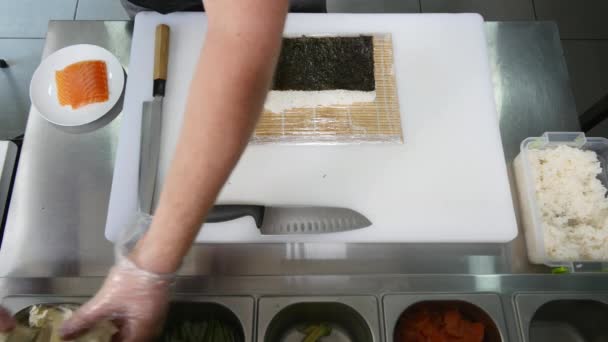 Руки делают длинный суши-ролл. Суши шеф-повар демонстрирует мастерство. Знаменитая японская кухня. вид сверху — стоковое видео