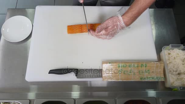 Chef en el restaurante preparando y cortando rollos de sushi comida saludable. vista superior — Vídeos de Stock