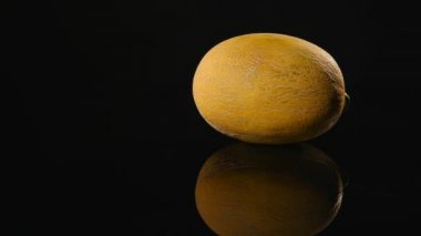 Siyah bir zemin üzerine sarı kavun döner, yakın çekim