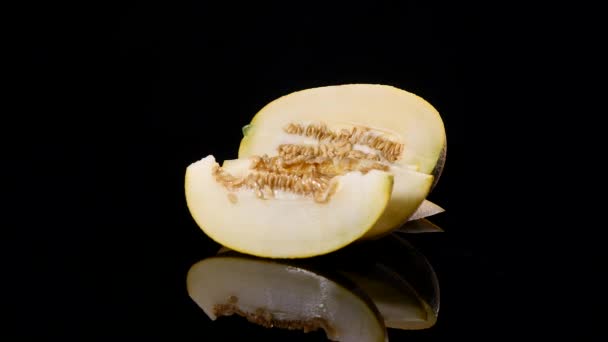 Un melón jugoso brillante. La mitad de la pulpa madura rotan sobre el fondo negro. Corta el melón. Ingredientes naturales y ecológicos — Vídeos de Stock