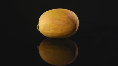 Siyah bir zemin üzerine sarı kavun döner, yakın çekim