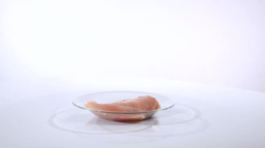 Beyaz bir arka plan üzerinde bir cam tabakta tavuk fileto döner