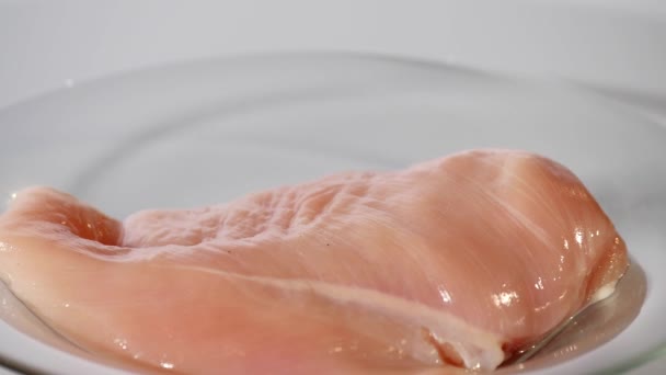 Chicken fillet in a glass plate turns on a white background, close up — Stock Video