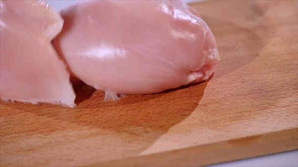 2 morceaux de filet de poulet cru tombent sur une planche en bois, au ralenti — Video