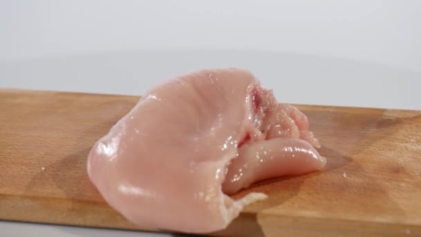 2 куска сырого куриного филе падает на деревянную доску, замедленная съемка — стоковое видео