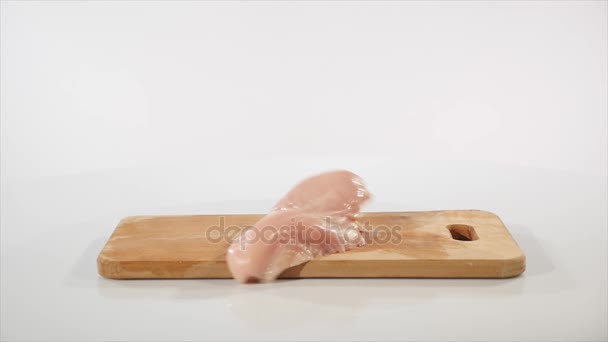 2 trozos de filete de pollo crudo cae sobre una tabla de madera, cámara lenta — Vídeo de stock
