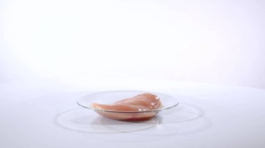 Beyaz bir arka plan üzerinde bir cam tabakta tavuk fileto döner