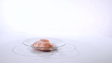 Beyaz bir arka plan üzerinde bir cam tabakta tavuk fileto döner